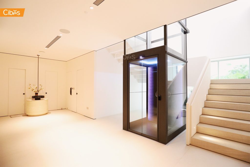 Modern glass lift in a bright, minimalist interior next to a staircase