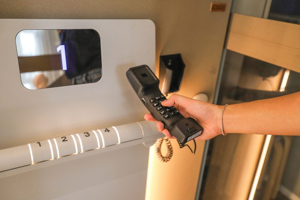 Hand holding an emergency intercom inside a glass lift
